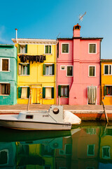 Typical colorful houses in front of canal with boat in Burano