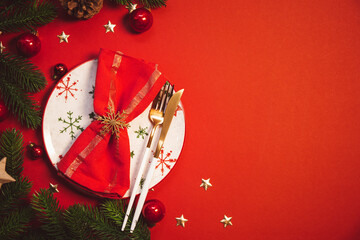 New Year and Christmas table setting concept. Empty plate and red napkin on festive red christmas table top view, copy space for text