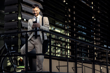 Portrait of business man with bicycle standing in front of office building.