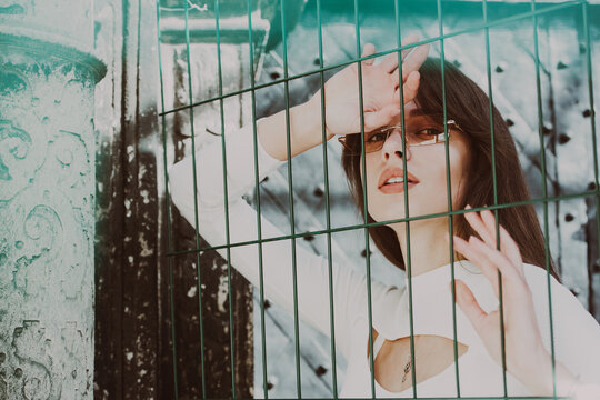 Close-up portrait of woman a in a white blause near a metal grid