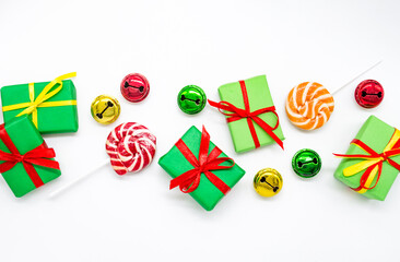 Happy holidays: gifts with lollipops and red, green, golden bells on a white background, copy space. The concept of Christmas, sales, children parties