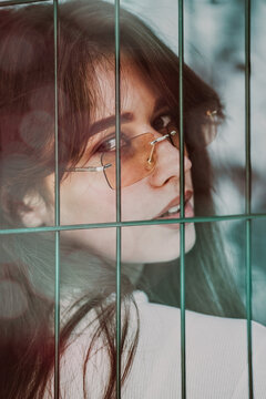 Close-up portrait of woman a in a white blause near a metal grid