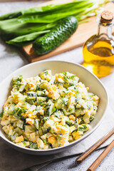 Healthy salad of green wild leek, poached egg and cucumber, close up. Wild garlic salad with boiled eggs