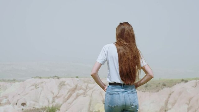 Young girl walking alone against a background of hills and mountains