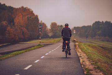 Fototapeta premium Person riding a bicycle on a road in autumn