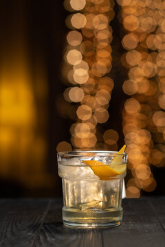 Classic White Cocktail in a glass with ice and orange peel on a brown light background