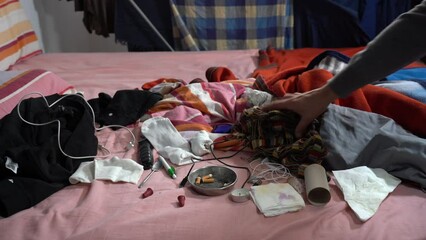 Dirty and messy bedroom. Unmade sleeping bed with various items scattered around in a dirty and neglected house, . Domestic cleaning and personal well-being. ashtray with unlit cigarettes and objects 