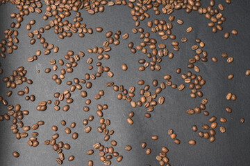 Evenly scattered coffee beans on a black background.