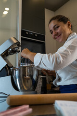 vertical shot of enterprising young woman pastry chef adding chocolate in the planetary mixer