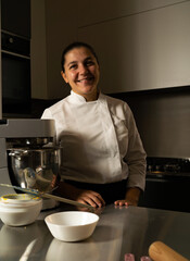 Fototapeta na wymiar vertical Portrait of a smiling pastry chef in her workplace, copy space