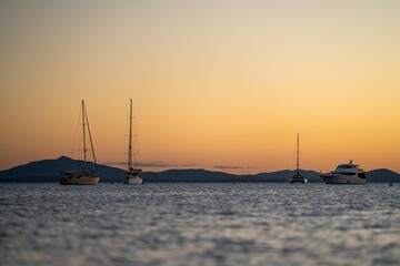 sunset over the ocean in golden light with waves and yachts