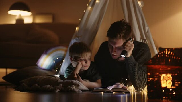 Careful Loving Father Is Reading Fairytale For His Little Son, Dad And Boy Inside Teepee Tent In Home