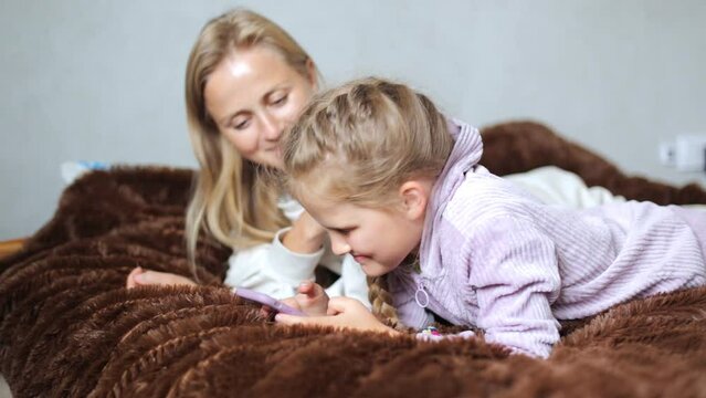 Happy mom and daughter laugh and look at the phone. Funny videos on the phone that daughter and mother watch