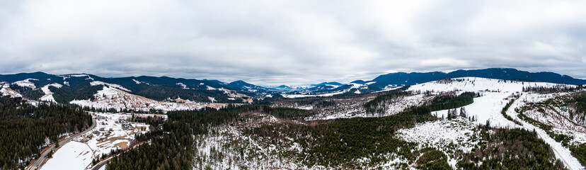 Carpathian slopes in the snow, view of the mountains from above, drone panorama.