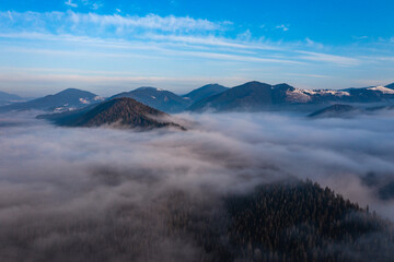 A panoramic view from above of the mountain peaks in thick clouds.