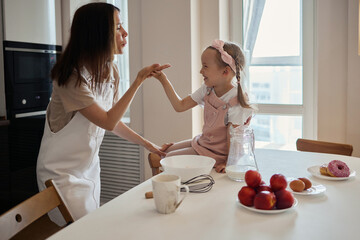 An image of a young woman and her little cute daughter are cooking in the kitchen. Have fun...