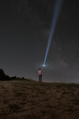 Beautiful night sky with stars and silhouette of a standing alone man on the mountain with a lantern. Blue milky way and man on the hill. Background with galaxy and silhouette of a man. 