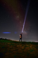 Beautiful night sky with stars and silhouette of a standing alone woman on the mountain with a lantern. Blue milky way and man on the hill. Background with galaxy and silhouette of a man. 