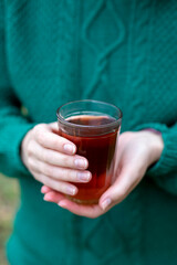 Glass of black tea in woman's hand outdoor. Close up