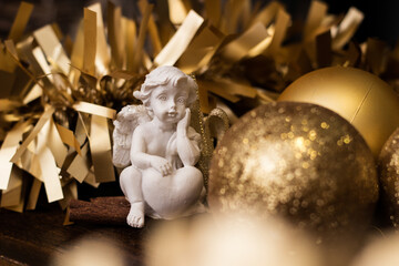 Angel arround golden Christmas balls with gold tinsel