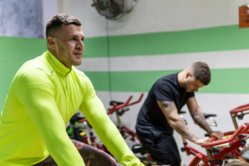 Two men doing static bycicle in the gym. Healthy lifestyle, workout concept