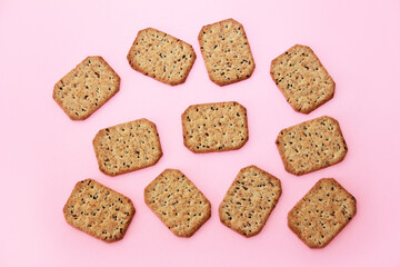Square dry crackers with seeds for dietary nutrition on a pink background