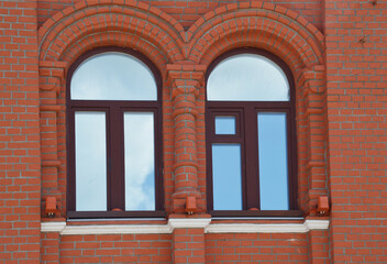 Facade element of a red brick building with two arched windows. Restoration of houses. Architecture.
