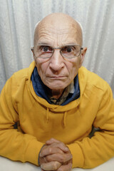 Vertical portrait of old strange funny person looking to camera with distorted face low angle view