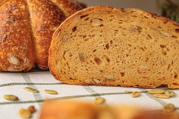 Slices of craft pumpkin bread  with pumpkin seeds . Homemade wholemeal rye yeast-free bread on a white striped towel