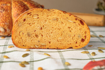 Slices of craft pumpkin bread  with pumpkin seeds . Homemade wholemeal rye yeast-free bread on a white striped towel