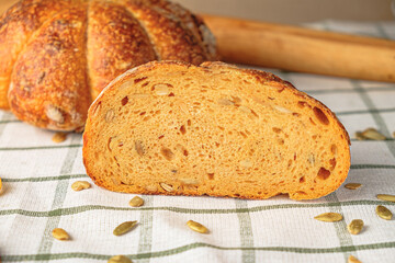Slices of craft pumpkin bread  with pumpkin seeds . Homemade wholemeal rye yeast-free bread on a white striped towel