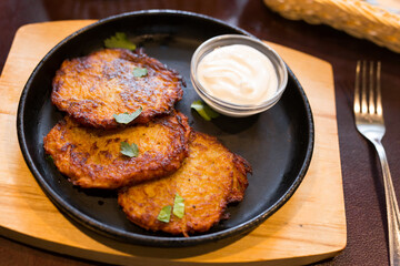 Fried grated potato pancakes with sour cream on frying pan