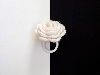 Close up one Crochet white rose flower scrunchy on modern bicolor black and white background,...