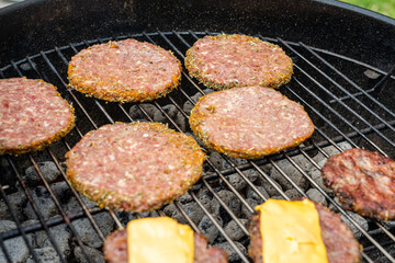 Selective focus of fresh delicious burger cutlets with cheese grilling on bbq grill