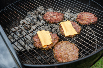 Selective focus of fresh delicious burger cutlets with cheese grilling on bbq grill