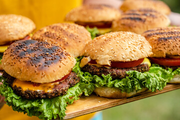 Closeup of homemade burgers made from fresh vegetables on wood plate holding women