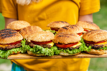 Closeup of homemade burgers made from fresh vegetables on wood plate holding women