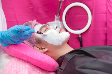 An Esthetician applies post treatment collagen cream with a brush. Procedure after a diamond peel...