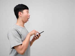 Man grey shirt feels shocked gesture press smart phone in his hand side view isolated