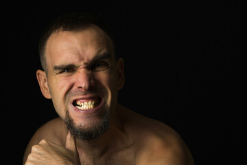 Naklejka premium Caucasian bearded man with angry expression threatening to kill. A man with an aggressive look, making signs with his thumb at his throat. Black background