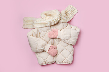 Kids warm puffer jacket with scarf on pink background. Stylish childrens outerwear. Winter fashion...