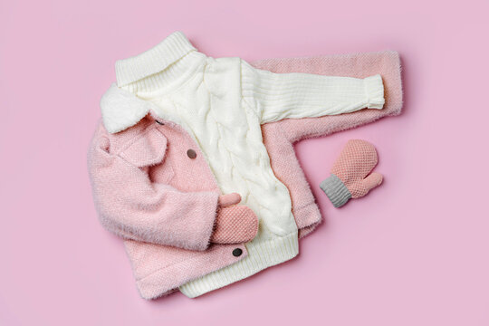 Kids fur jacket with warm sweater on pink background. Stylish childrens outerwear. Winter fashion outfit