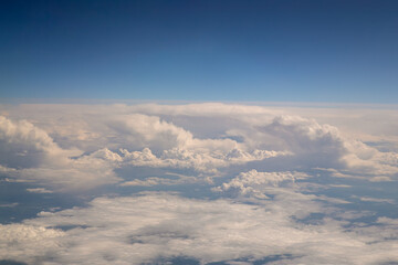 View from the window of an airplane, on a plane taking off, on a beautiful cloudy sky. Airplane or plane window with wing and cloudy sky behind