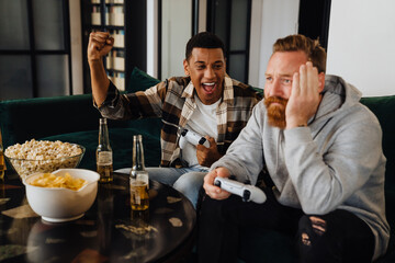 Young african man playing video game with his friend and winning