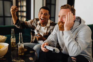Upset white ginger man playing video game with his african friend and losing
