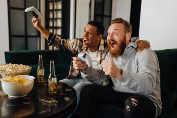 Two excited men gesturing as winners while playing video games at home