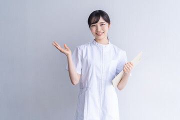 案内のポーズをするナース服の女性