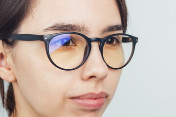 Young girl with poor eyesight wearing glasses for vision. Glasses protect the eyes from the computer monitor