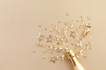 Champagne bottle with gold confetti stars, holiday decoration and party streamers on light festive background. Christmas, birthday or New Year concept. - 544375805