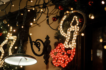 Stylish christmas candle illumination and festive lights on fir branches in evening outdoor. Modern christmas decor in city street. Atmospheric winter holidays in Europe. Merry Christmas!